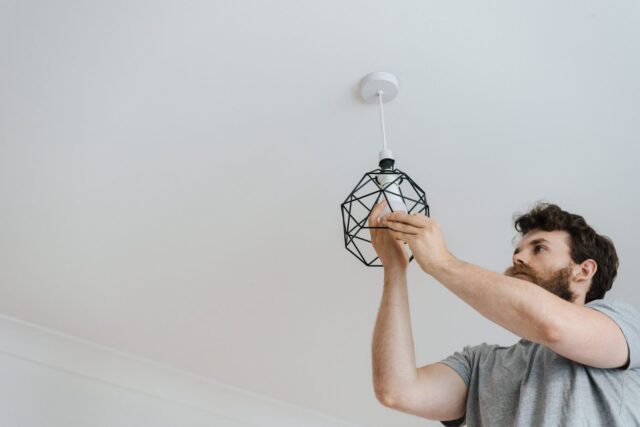 A shot from below of a bearded man screwing in a lightbulb | Specialized Memphis A shot from below of a bearded man screwing in a lightbulb