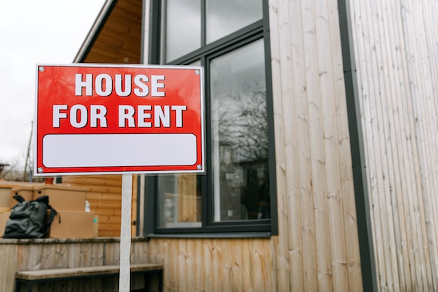 Red-House-For-Rent-sign-in-front-of-a-wooden-house | Specialized Memphis Red “House For Rent” sign in front of a wooden house