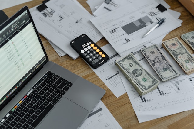 Documents-dollar-bills-a-calculator-and-a-laptop-on-a-table | Specialized Memphis Documents, dollar bills, a calculator and a laptop on a table